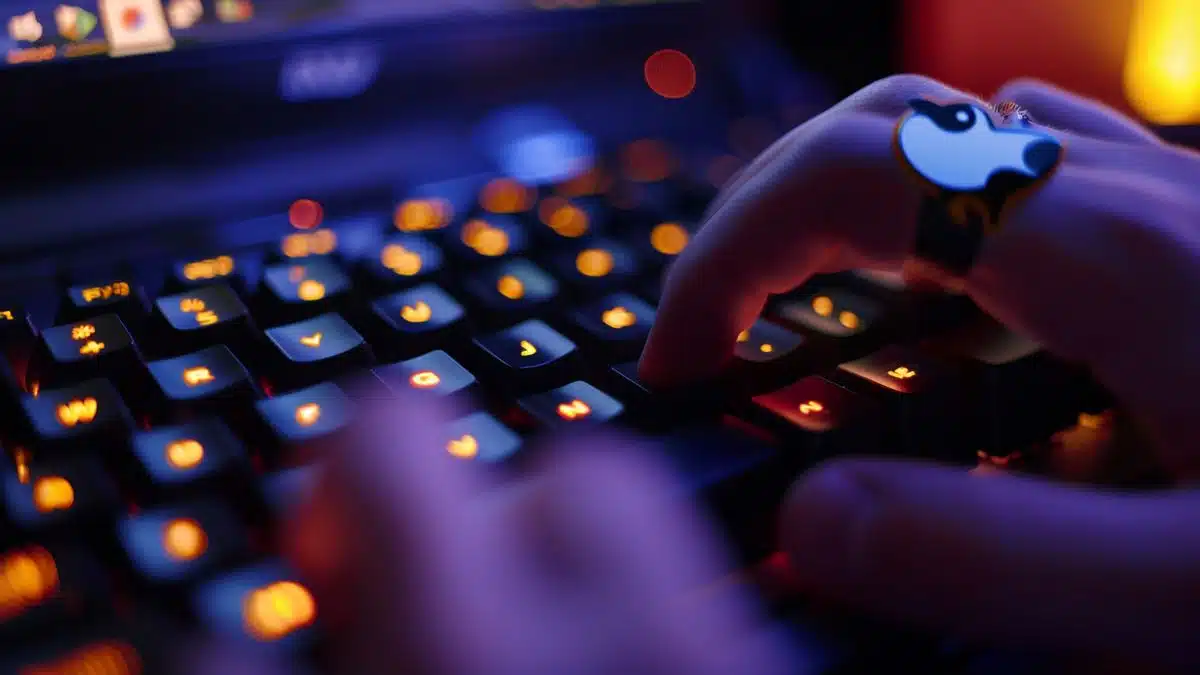 Hands typing on a keyboard with a Linux penguin sticker.